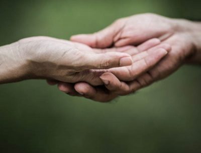two hands clasped against a green background