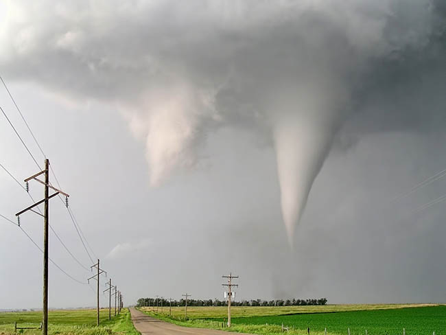 tornado myths, two funnel clouds hang down from clouds in a rural area.