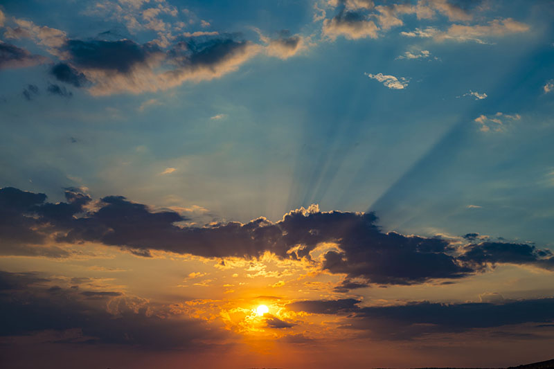 Colorful sunset in the blue sky.The rays of the sun breaking through the dark clouds. Abstract natural background. types of clouds